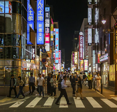 Bustling cityscape of Tokyo, Japan, illuminated by neon signs and busy crosswalks at night.