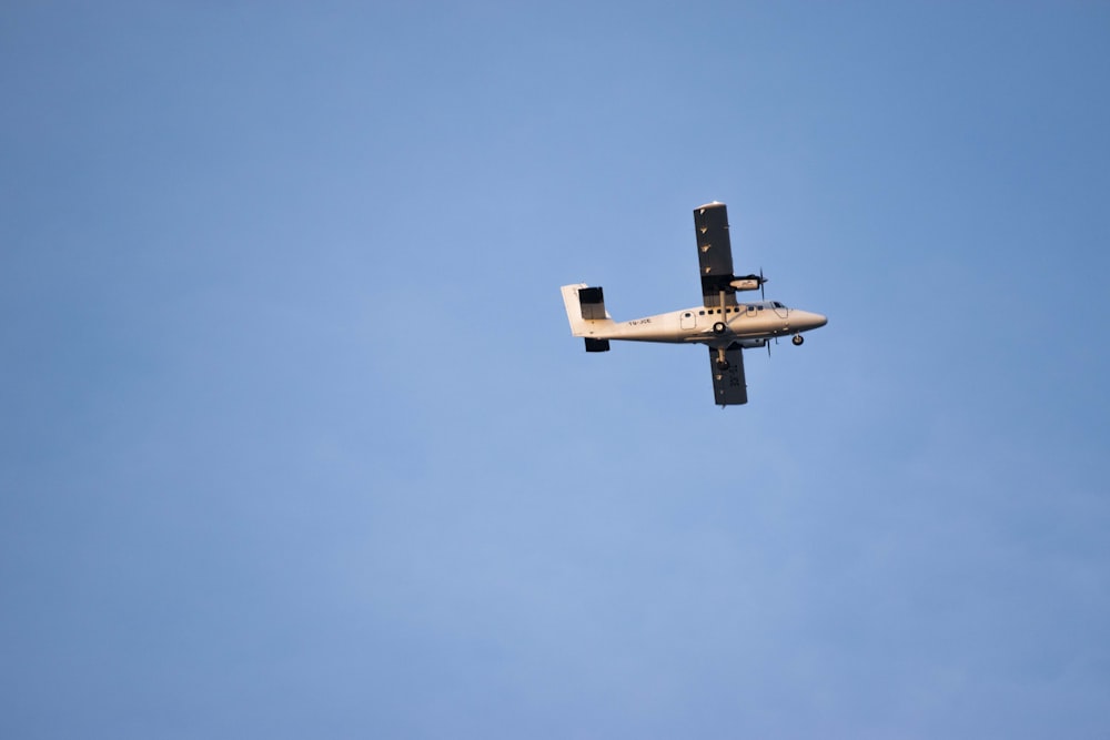 flying gray single-propeller plane during daytime