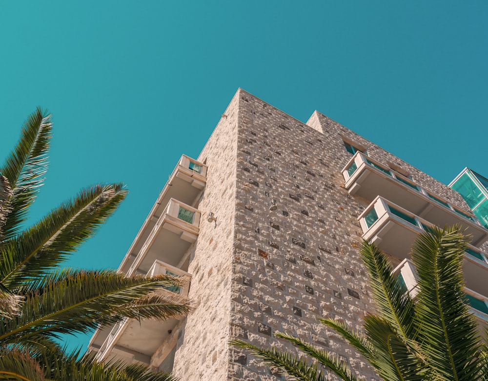 um edifício alto de tijolos com palmeiras à sua frente