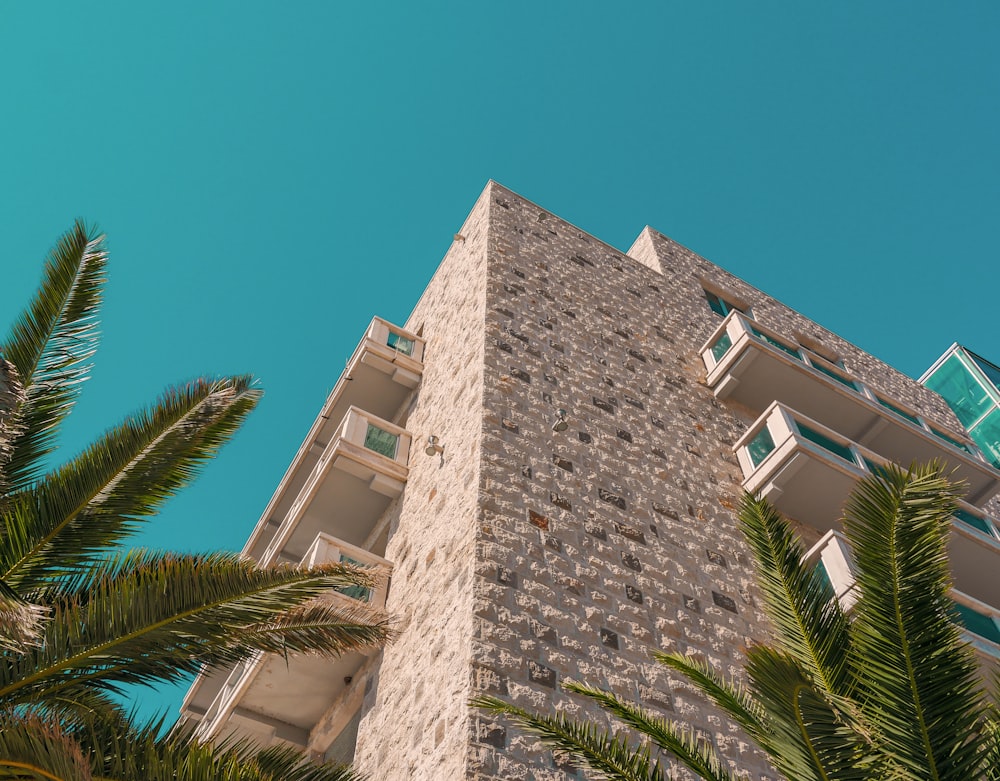 a tall brick building with palm trees in front of it