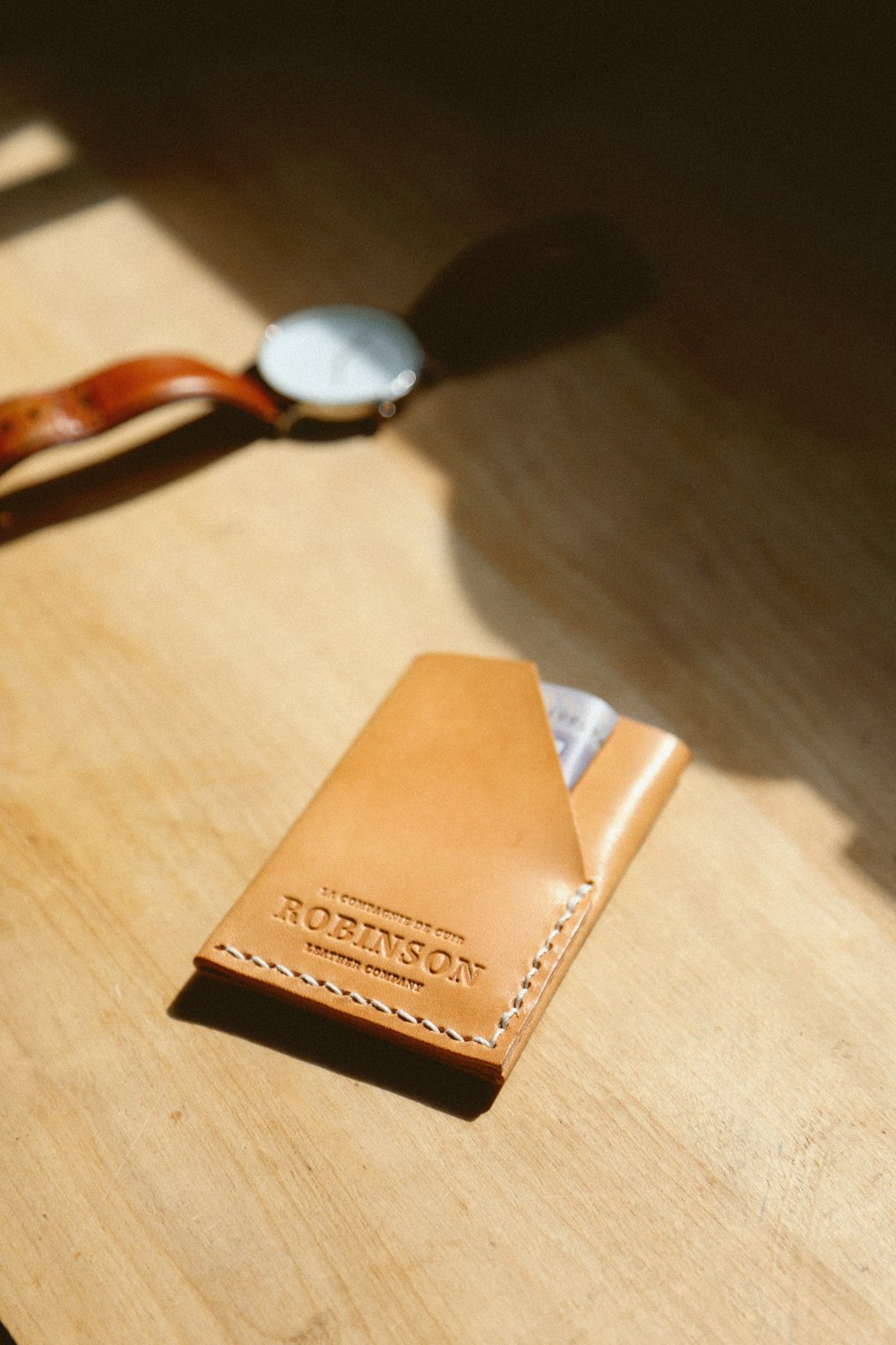 brown leather wallet beside watch on table