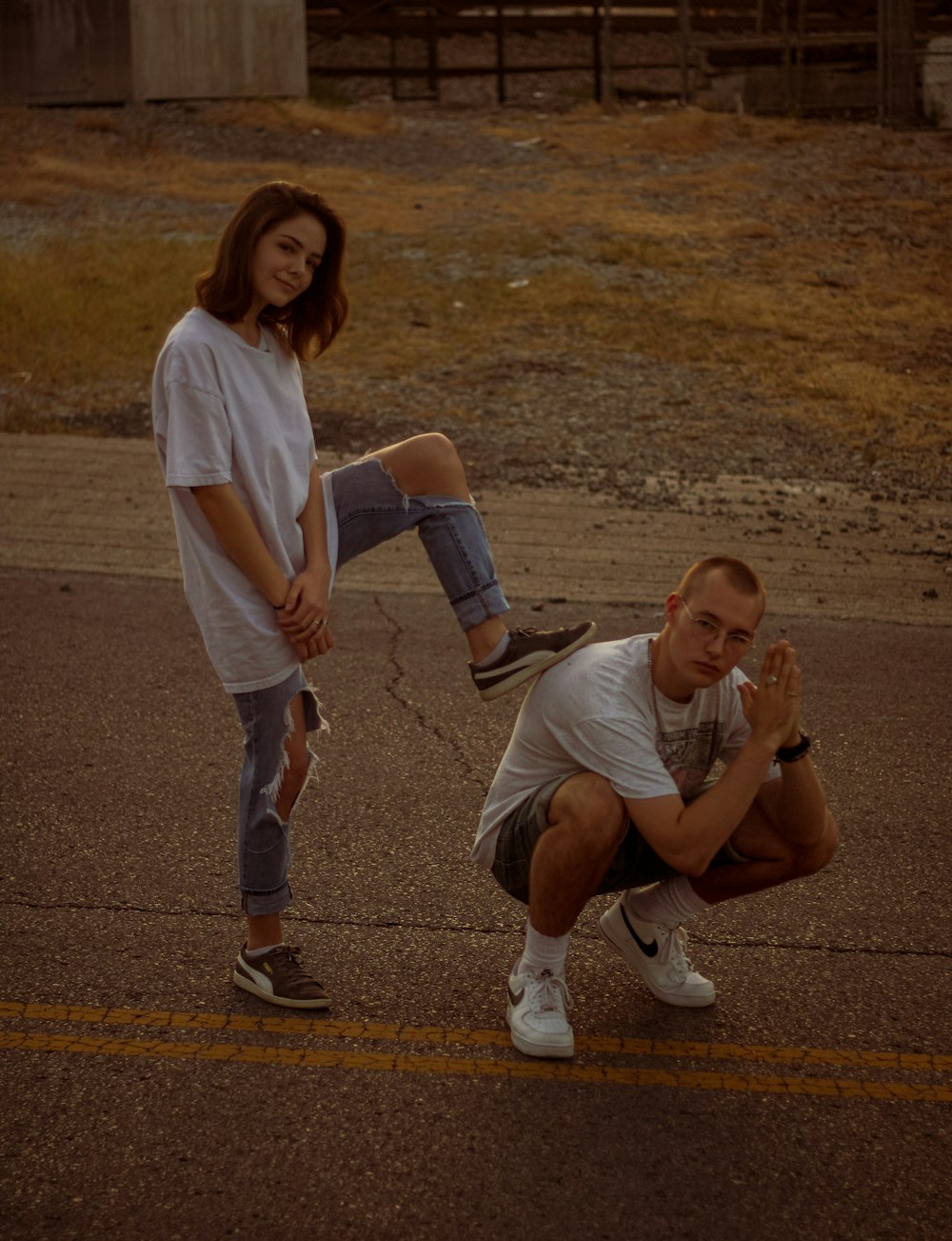 woman in white stepping on crouching man's back