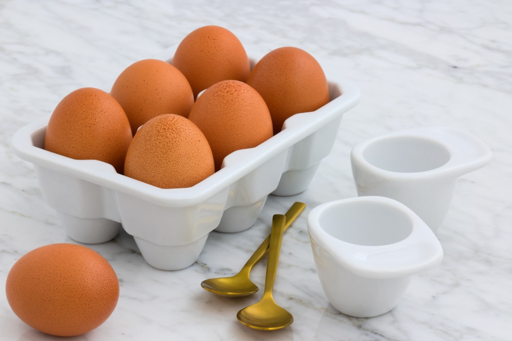 tray of brown eggs beside two spoons