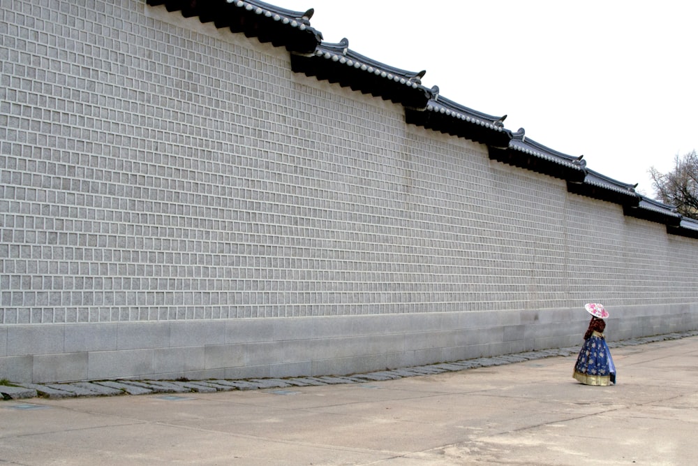 woman wearing traditional dress standing in front of gray concrete wall