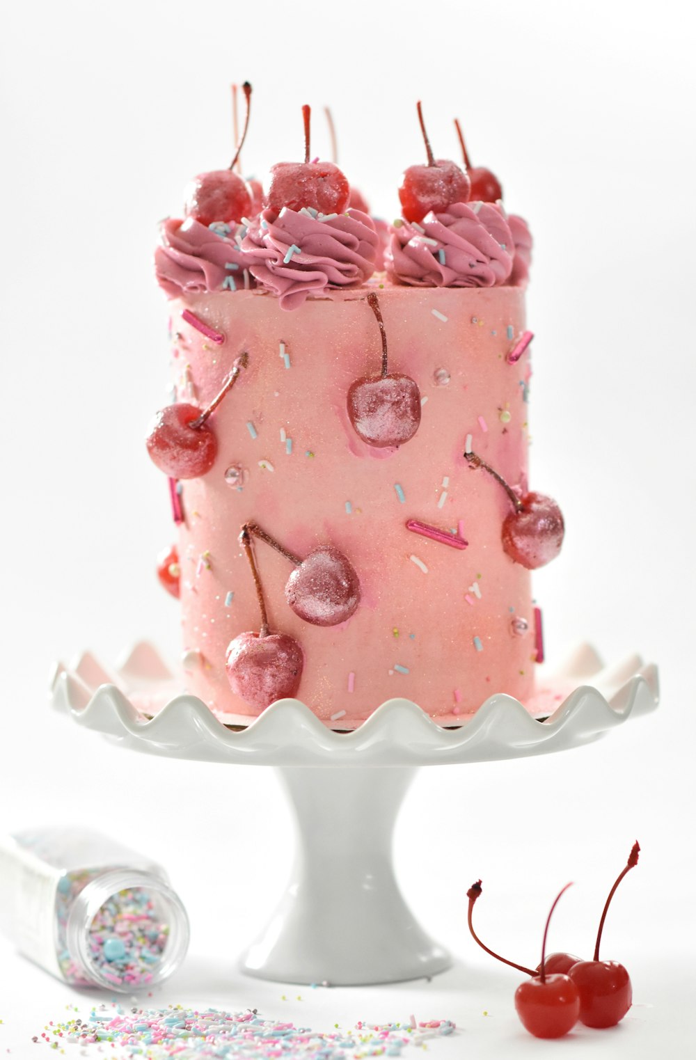 Torta di ciliegie rosa su vassoio per torte dai piedi bianchi