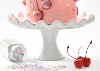 pink cherry cake on white footed cake tray