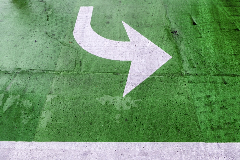 Una flecha blanca pintada en un estacionamiento verde