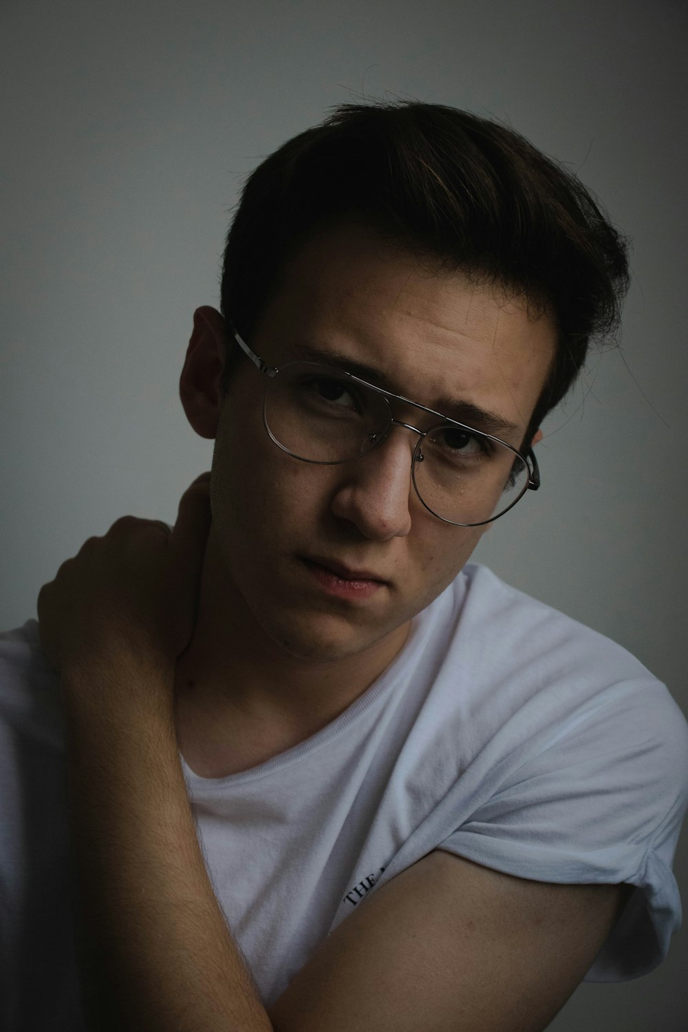 man wearing white t-shirt holding his neck