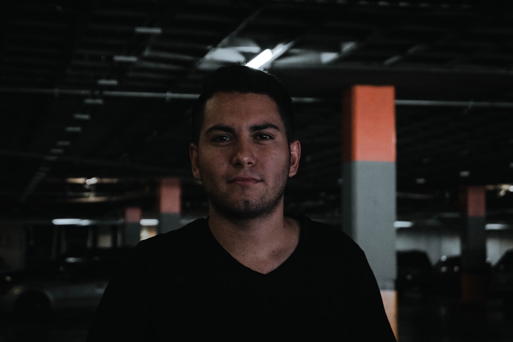 man wearing blue t-shirt standing inside building parking area