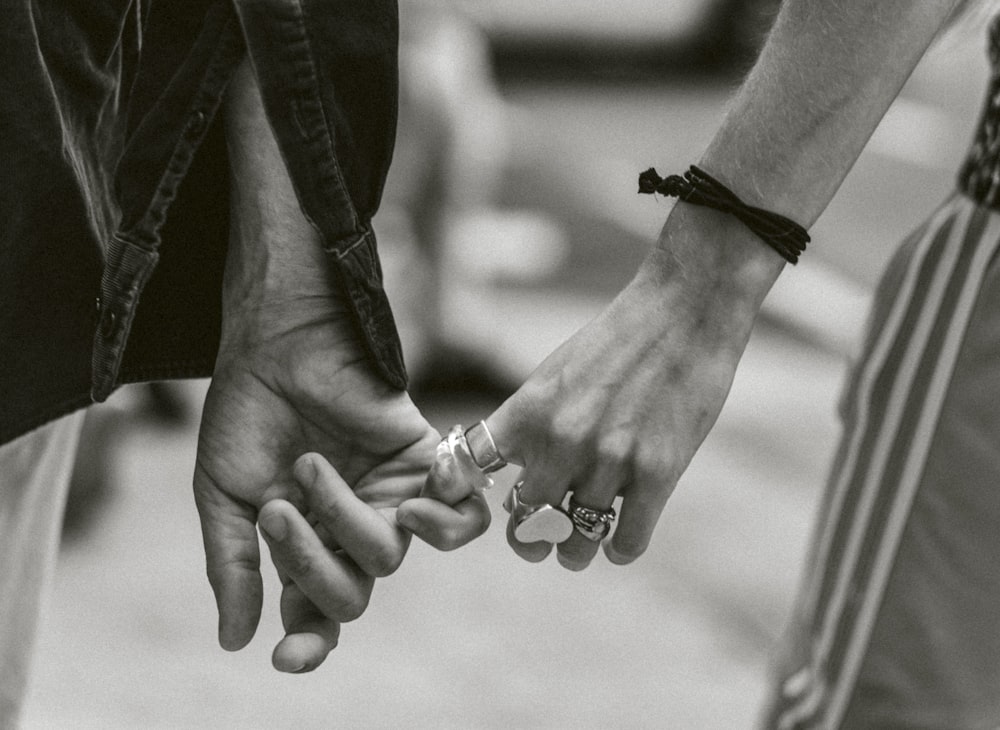 Photographie en niveaux de gris d’un couple se tenant la main en marchant