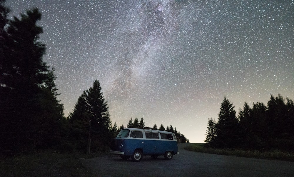 blue and white van near green trees during night time