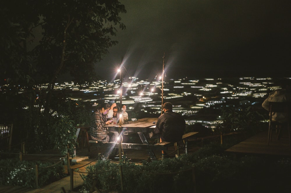 people sittnig in picnic table with lights during night time