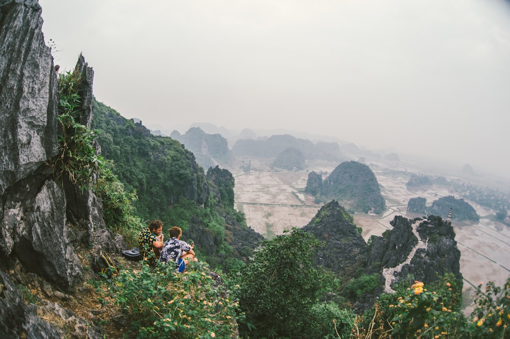Dos personas sentadas en la cima de la montaña durante el día