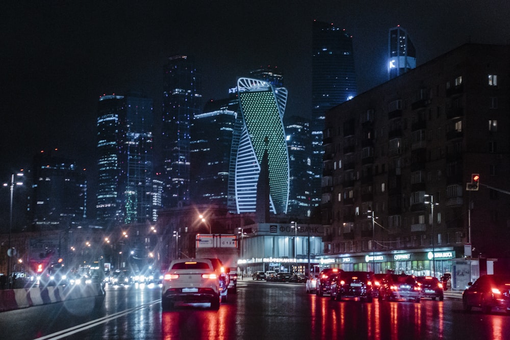 different vehicles on road viewing city with high-rise building during night time