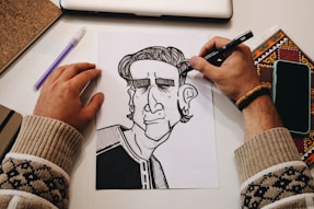 person holding pen drawing on white paper