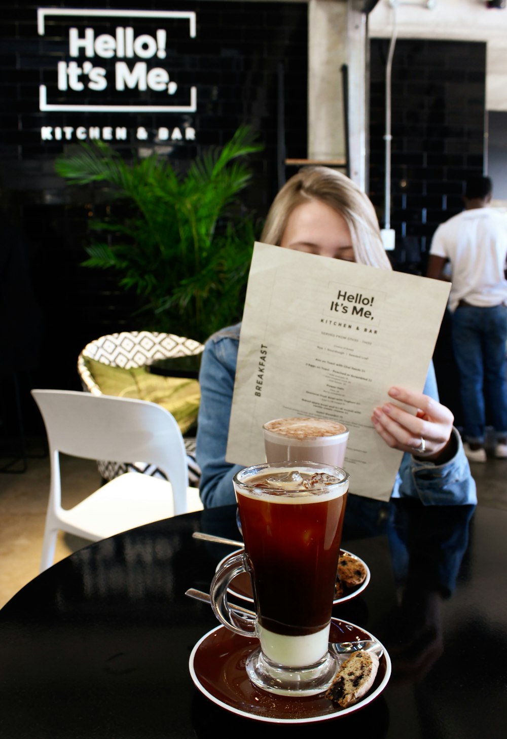 woman reading in paper siting beside table with drinks