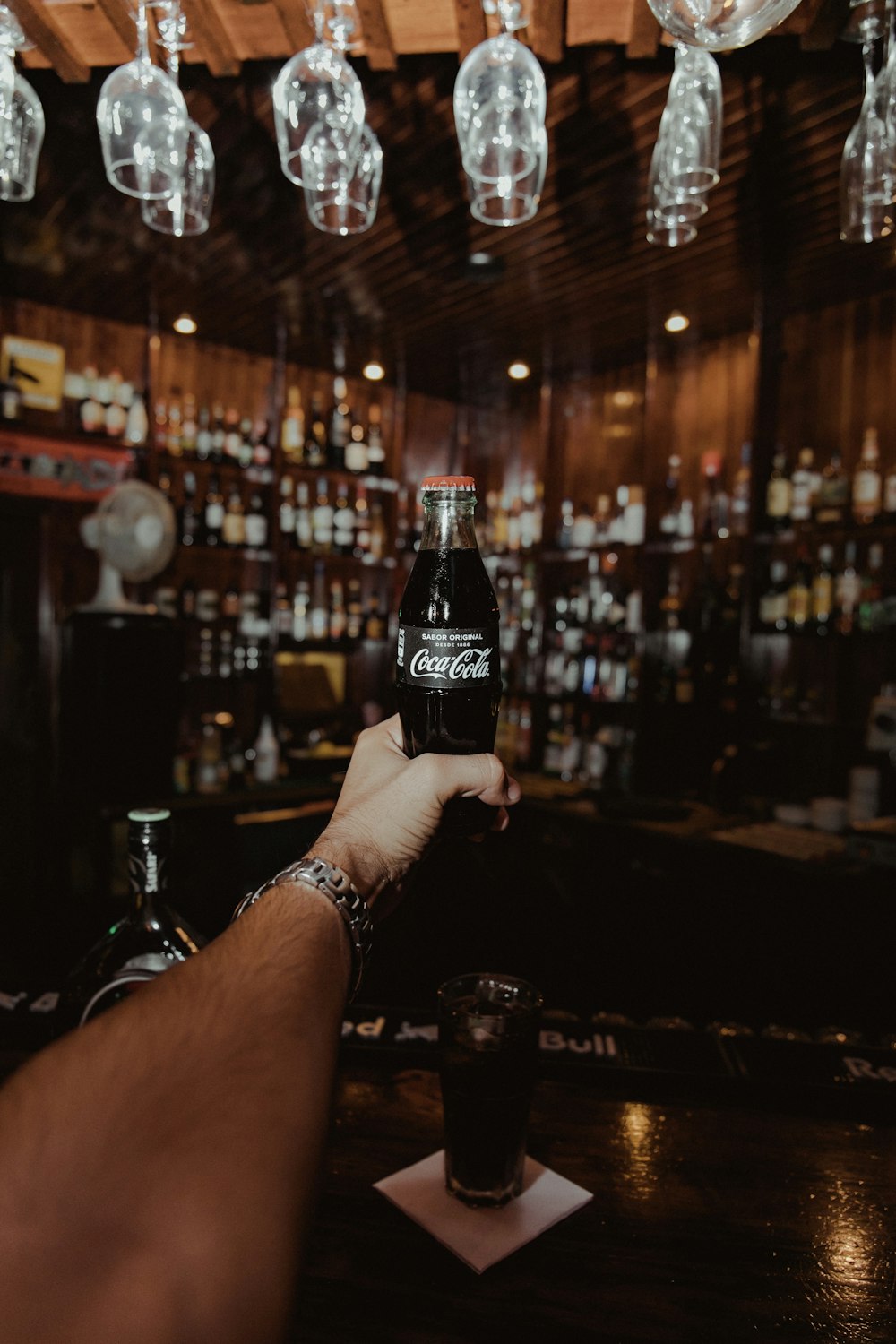 homem segurando garrafa de Coca-Cola dentro de bar