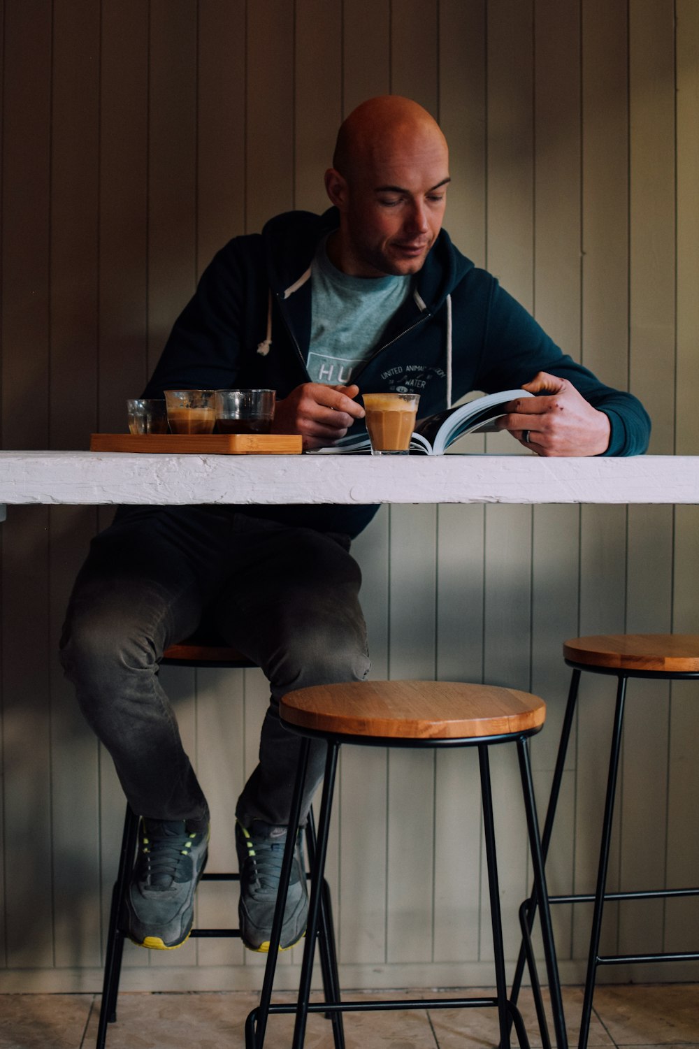 man reading book while sitting near white table