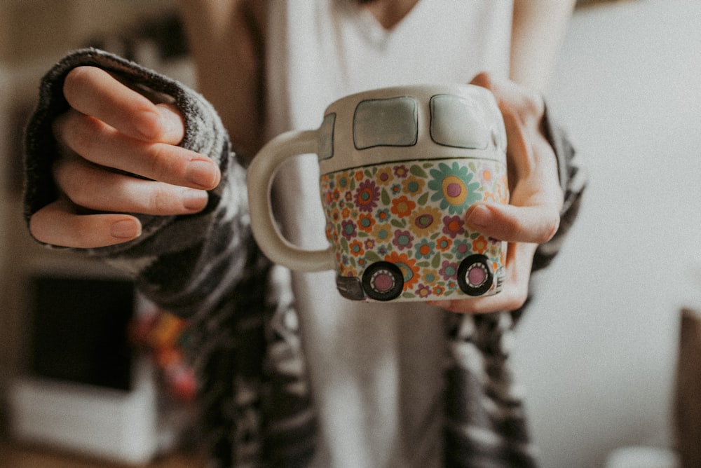 person holding white floral mug