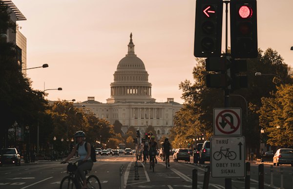 People biking on road and different vehicles viewing United States Capitol during daytime screenshot — Washington, DC, United States