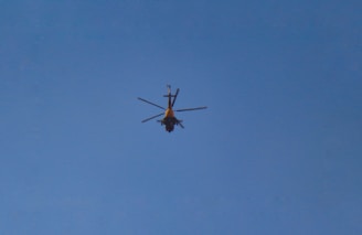A helicopter in flight against a clear blue sky.