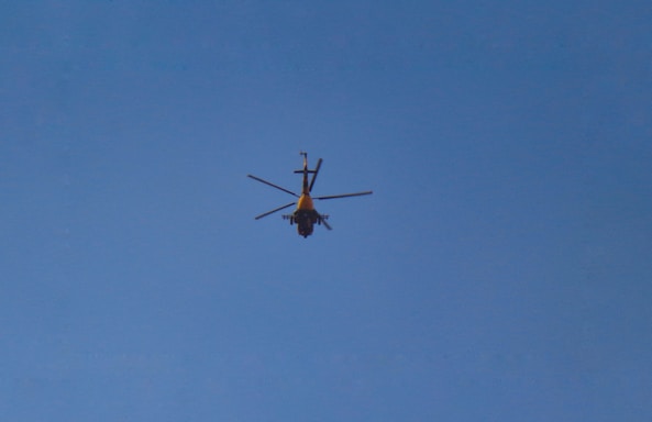 A helicopter in flight against a clear blue sky.