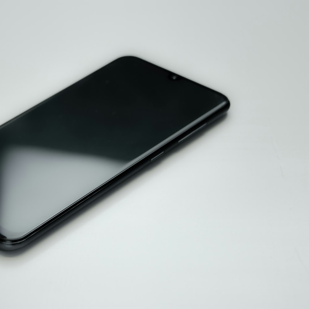 a black cell phone sitting on top of a white table