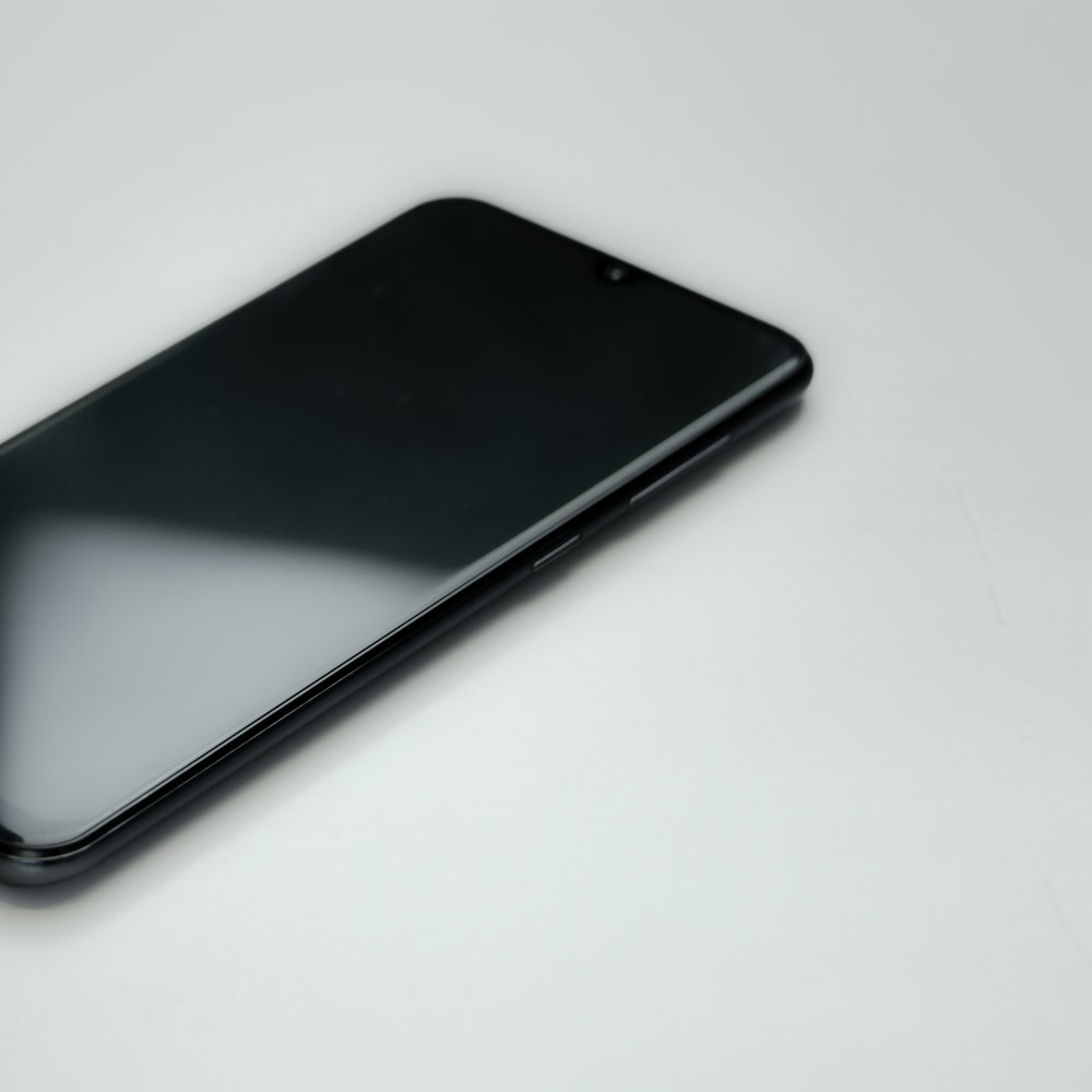 um celular preto sentado em cima de uma mesa branca