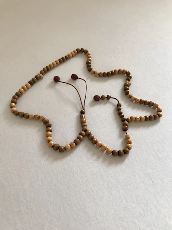 A collection of prayer beads and crosses arranged artistically on a textured fabric background.