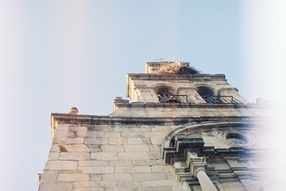 a tall brick building with a bird nest on top of it