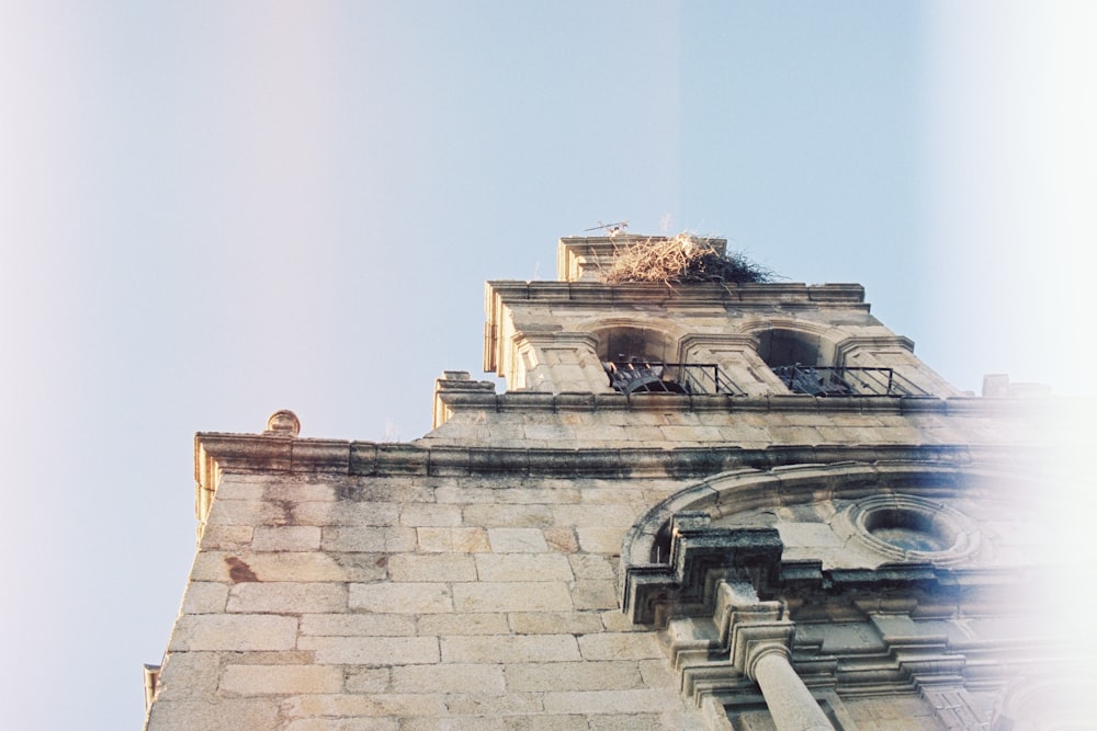 um edifício de tijolos altos com um ninho de pássaros em cima dele