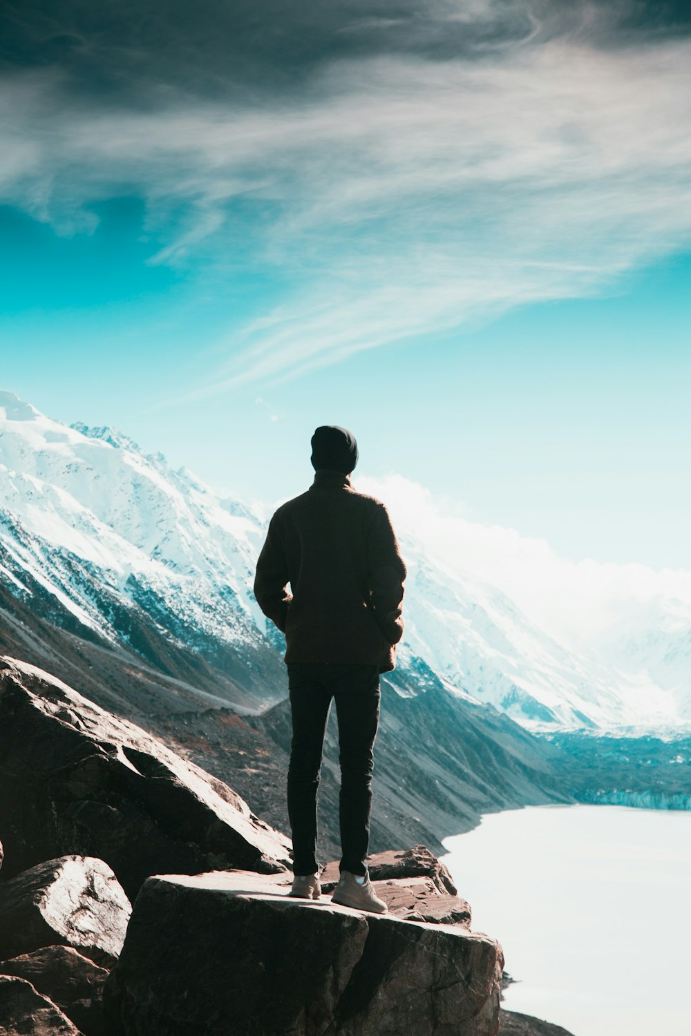 man on hill near lake