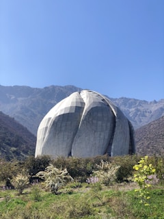 white dome structure near green field viewing mountain during daytime