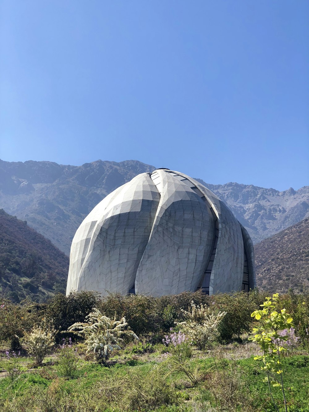 white dome structure near green field viewing mountain during daytime