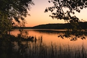 A calm lakeside scene at sunset, evoking a relaxed and unhurried atmosphere.