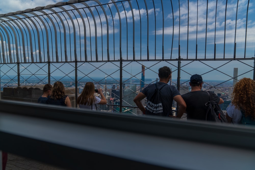 people sitting beside metal fence at daytime