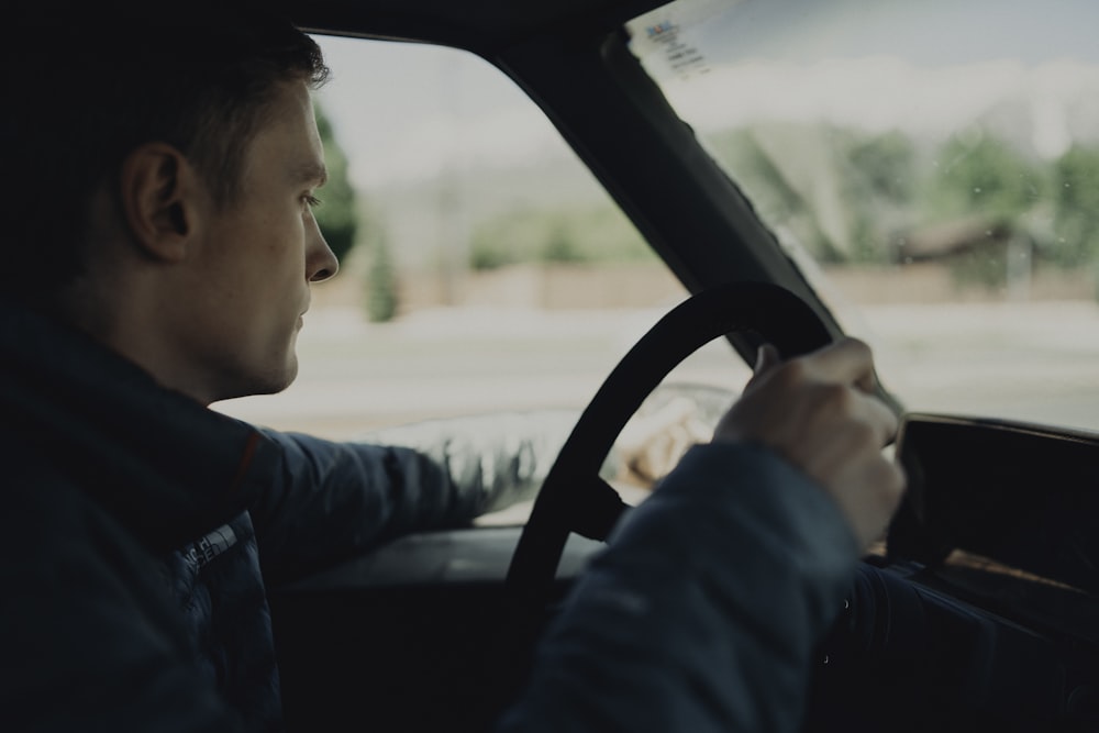 man holding steering wheel and wing mirror