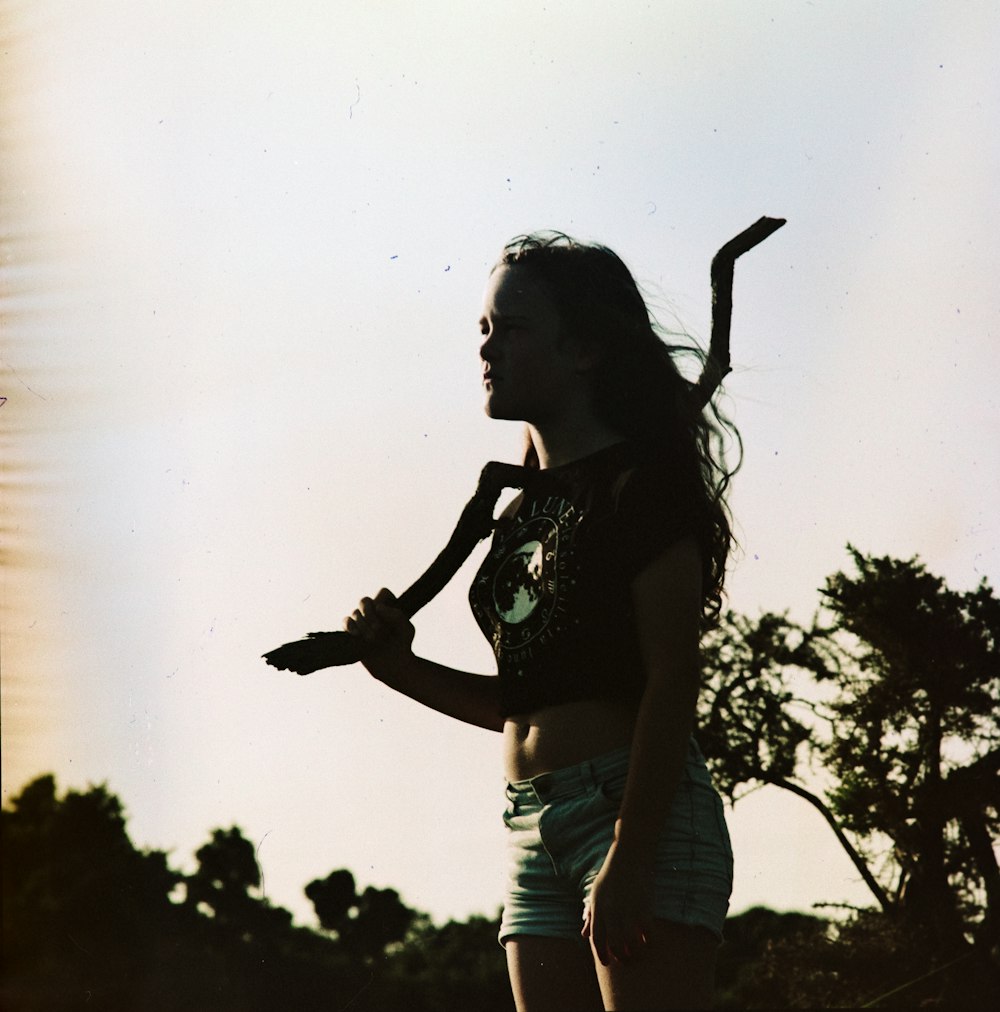 standing woman wearing white denim shorts holding stick