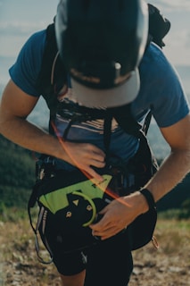 Hiker adjusting backpack straps on a mountain trail at sunrise.