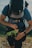 A person happily adjusting straps on a lightweight travel backpack in a park setting.