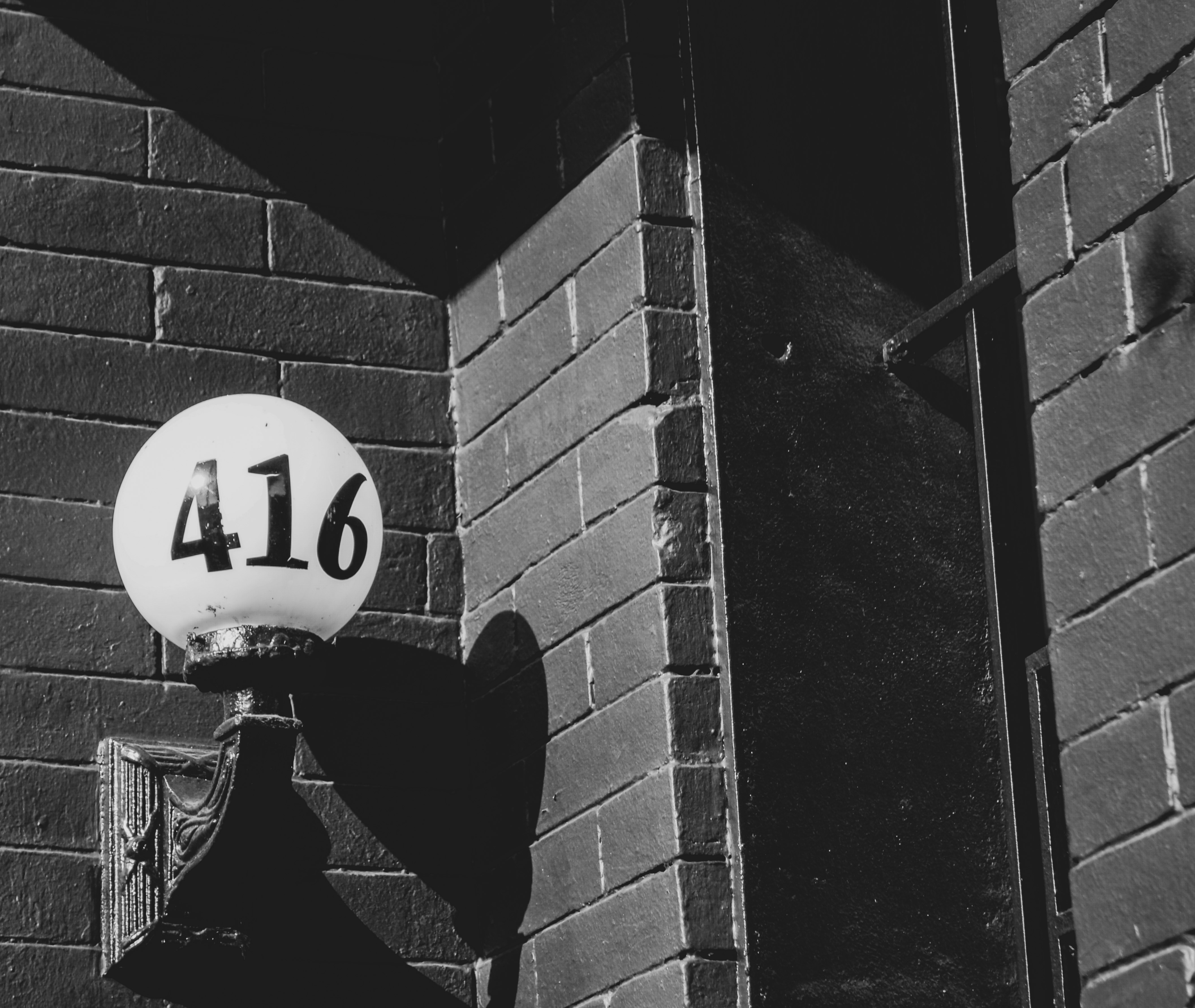 Black and white picture of building number painted on to a glass porch light belonging to New Leaf Smokeshop in Washington DC. 