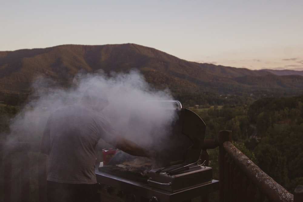 man barbecuing beside brown fence