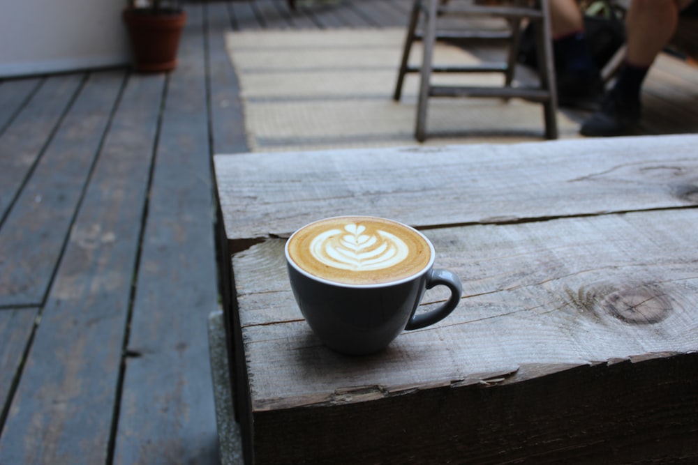 a cup of coffee sitting on top of a wooden table