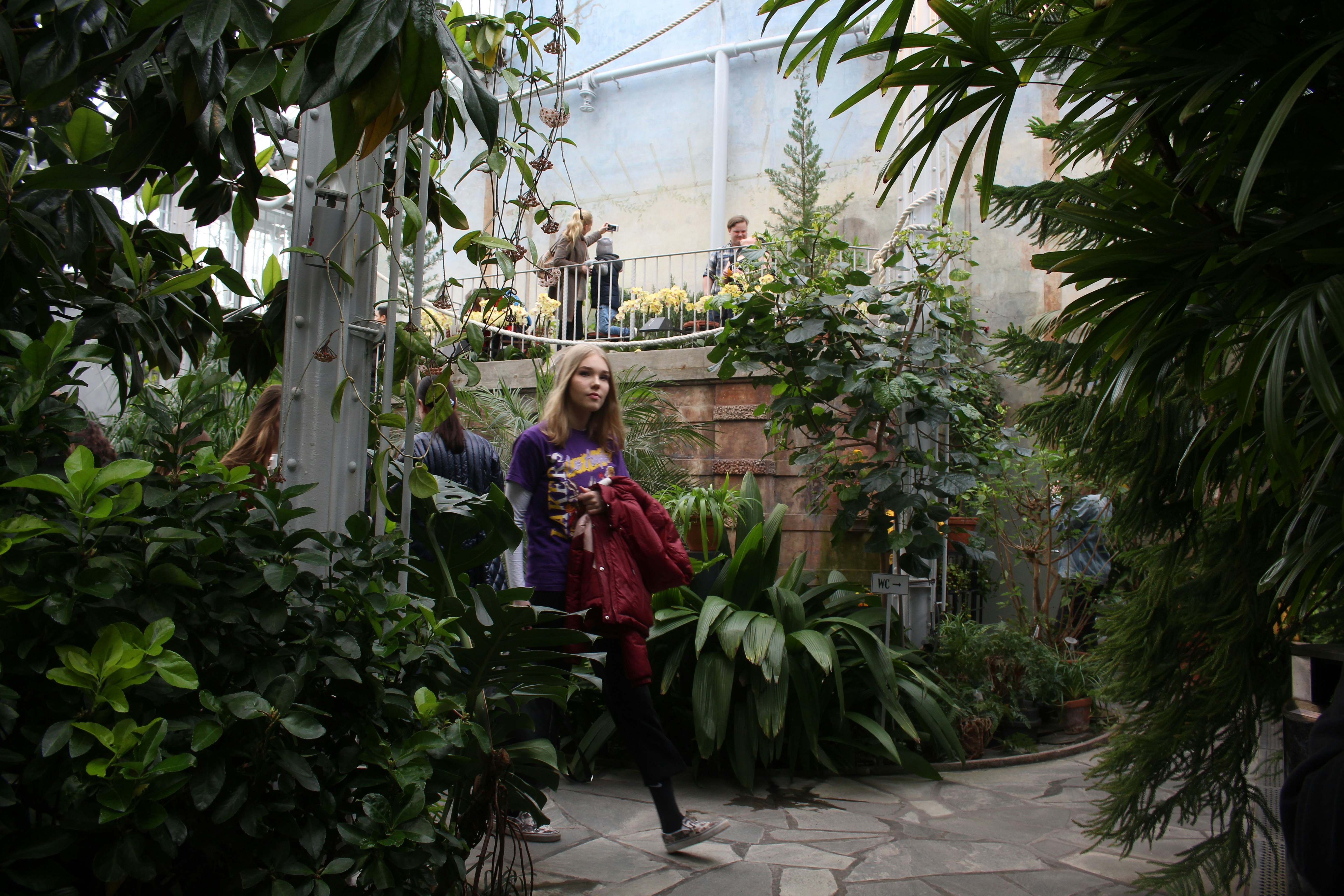 woman holding red jacket surrounded by plants