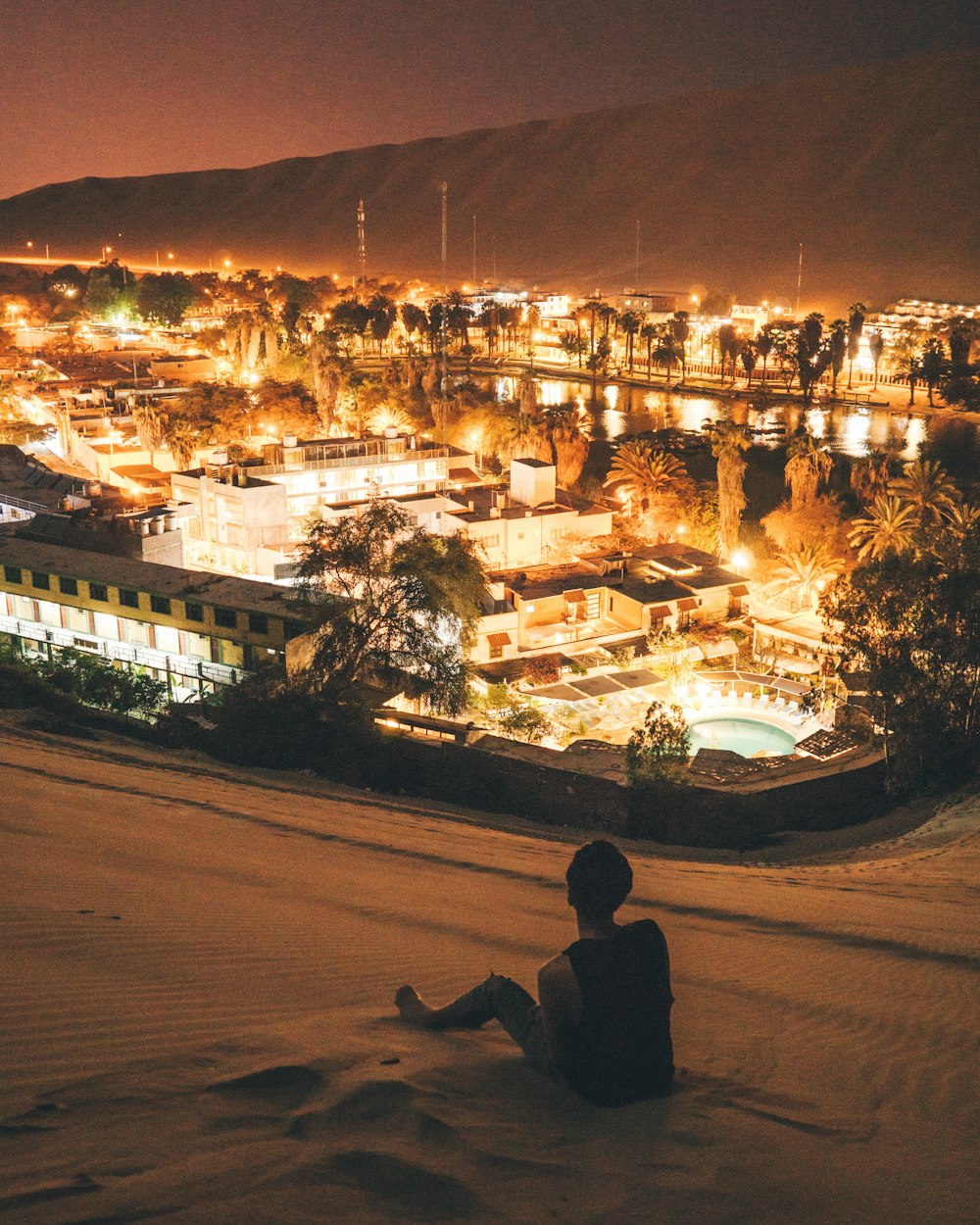 man sitting on sand at night