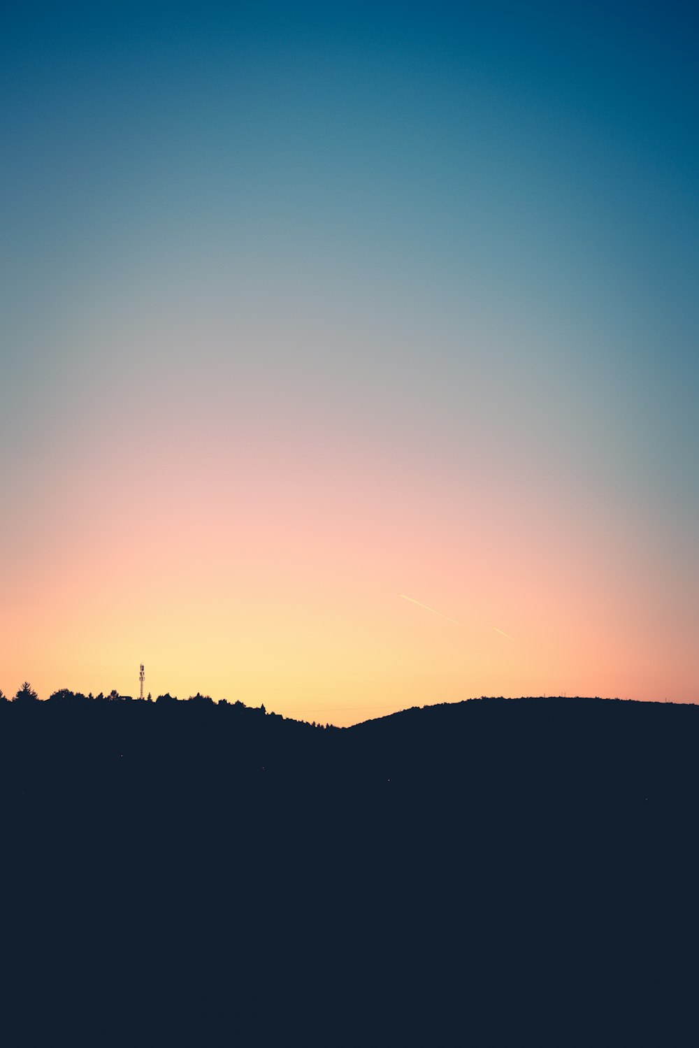 a plane is flying over a hill at sunset