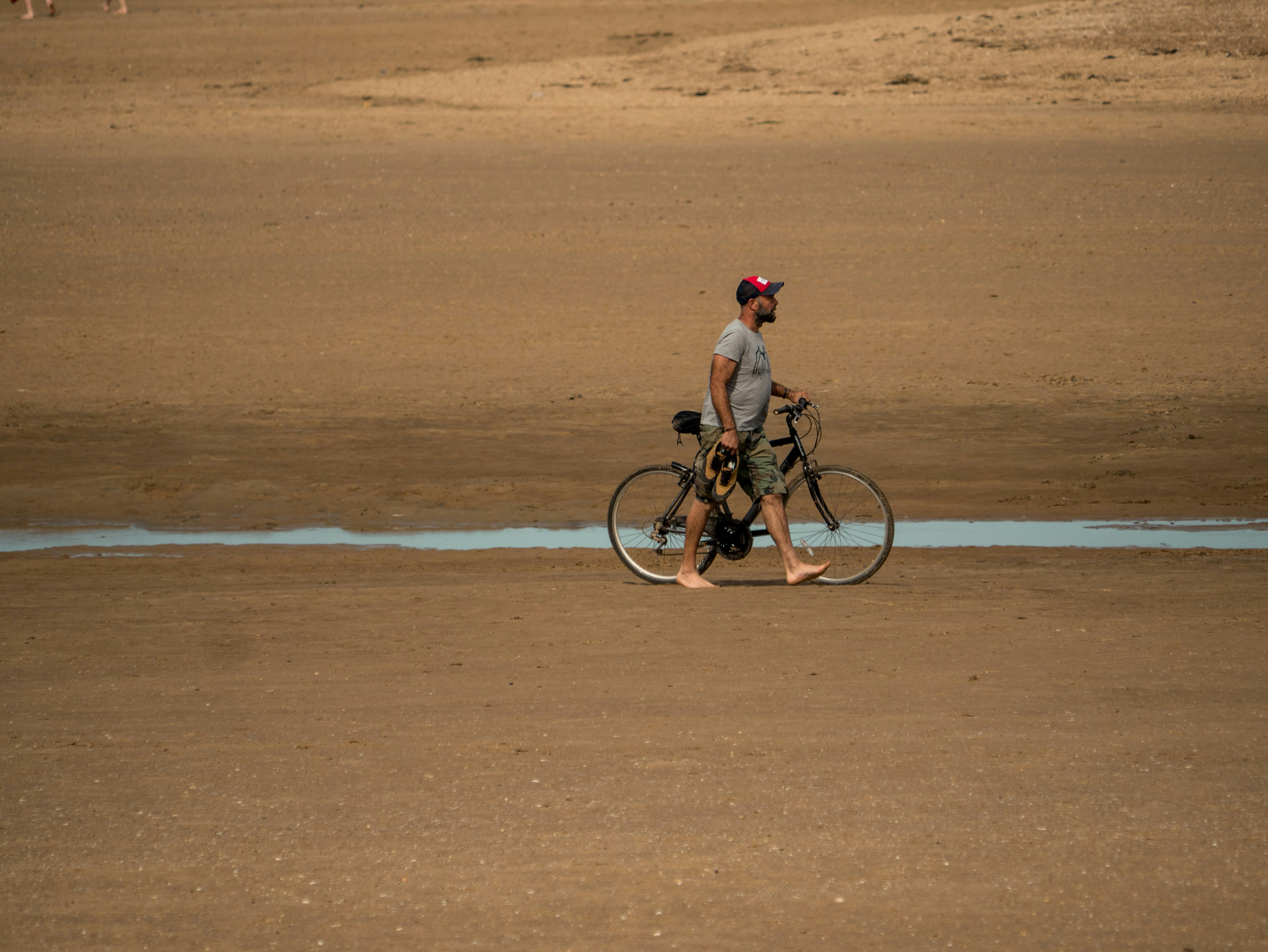 man walking on the field with his bike