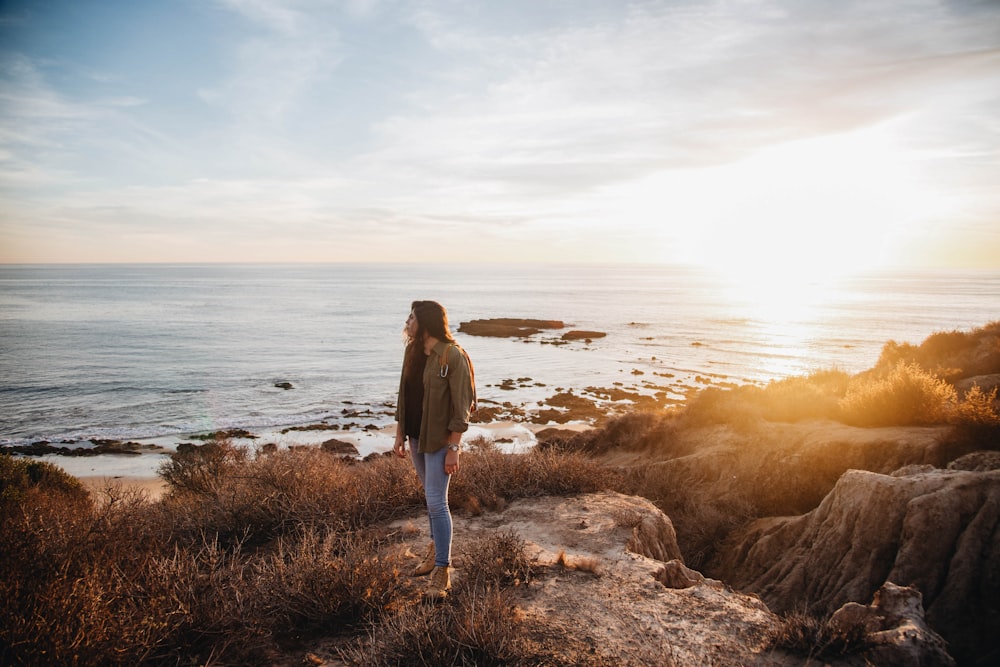 woman standing near body of water during golden hour