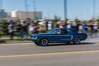 A classic muscle car in bright blue roaring down an open highway.