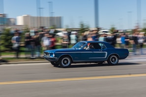 A classic muscle car in bright blue roaring down an open highway.